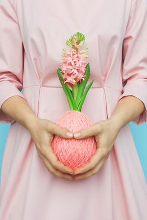 Magnificent blooming hyacinth in a ball of wool yarn color living coral in the shape of easter egg...