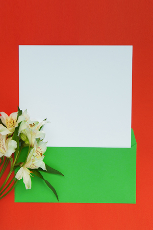 Beautiful alstroemeria on background of orange and white paper, green envelope with copy space for text. Top view, close up flat lay. Card concept.の写真素材