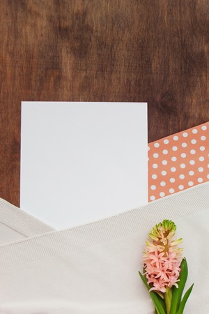Beautiful background of magnificent blooming hyacinth, coral and white paper polka dot with a beige plaid on a brown wooden background with copy space for text. Top view, close up. Card concept.の写真素材
