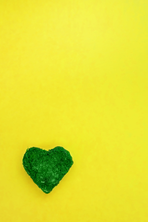 Colorful Easter frame with green moss heart on yellow background with copy space for text. Flat lay, close up, top view, vertical. Card concept, symbol of new lifeの写真素材