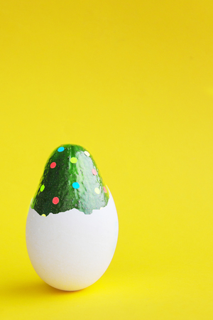 Beautiful creative decoration background idea with fresh green avocado polka dot confetti hatching from an egg on bright yellow paper. Holiday theme. Card concept. Closeup.Front view. Copy spaceの写真素材