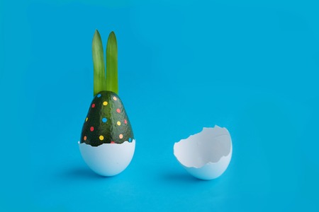 Beautiful creative decoration background idea with fresh green avocado rabbit polka dot confetti hatching from egg on blue.Card concept.Traditional decorative theme.Close up.Front view.Copy spaceの写真素材