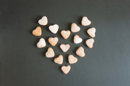 Fresh home baked cookies dessert, biscuit, gingerbread with powdered sugar in the shape of a heart on black backgroung. Valentines day kitchen food composition, top view flat lay copy spaceの写真素材