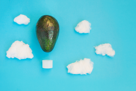 Beautiful creative decoration background idea with fresh green avocado hot air balloons with white clouds on blue paper sky. Closeup.Top view. Copy space, vibrant food, freedom and adventure conceptの写真素材