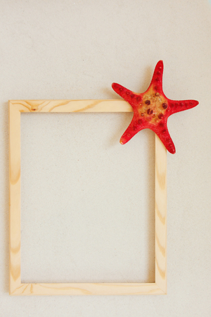 Red starfish and wooden frame on pure white fine beach sand. Sea relax background with place for text, copy space. Top view, copy spaceの写真素材