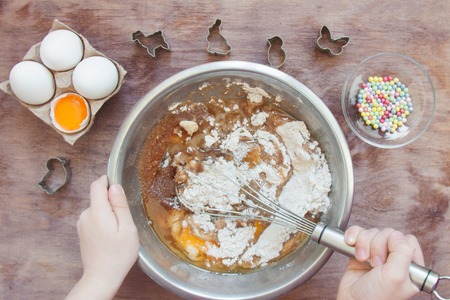 Baby making dough for Easter cookies dessert, biscuit with kitchen tools and products on a wooden...