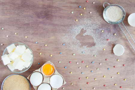 Products, kitchen appliances and tools on wooden table in the process of preparing Easter cookies dessert, biscuit, cake. Trace of flour or powdered sugar like rabbit . Top view flatlay, copy space.の写真素材