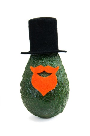 Fresh avocado in an elegant suit of black hat, beard and mustache on bright background. Minimal concept for wedding holidays card, party invitations. Front view, close up, isolatedの写真素材
