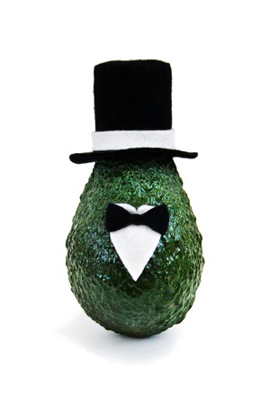 Fresh avocado in an elegant suit of black and white hats, shirts and bow ties on bright green background. Minimal concept for wedding holidays card, party invitations. Front view, close up, isolatedの写真素材