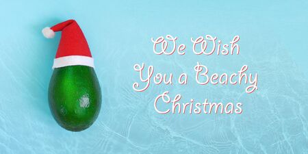 Fresh green avocado in a red and white Santa Claus hat. Christmas card concept. Water texture. Closeup. Top view. Copy space. Greeting template.の写真素材