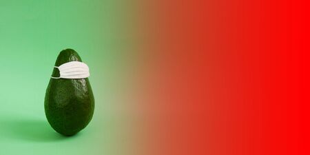 Green avocado in a white medical mask on an empty background for inscriptions. The concept of protecting a person health from the virus, bacteria and allergen. Copy space, front view, bannerの写真素材