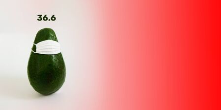 Green avocado in a white medical mask on an empty background for inscriptions. The concept of protecting a person health from the virus and bacteria. Copy space, front view, bannerの写真素材