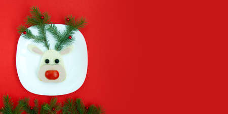 Funny Christmas sandwich for a child or party in the form of deer sausage, bread, vegetables . With branches of Christmas trees and decorations, top view, copy spaceの写真素材