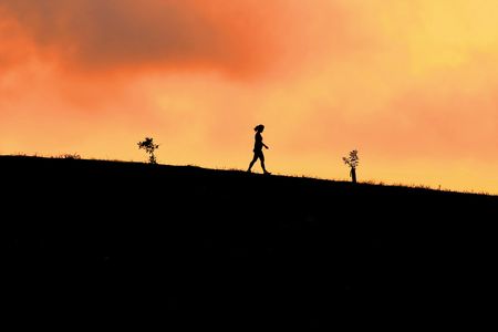 A silhouetted shot of a girl walking on rocks at the beachの写真素材