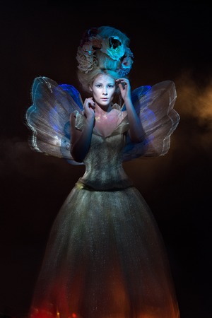 beautiful sexy cute gentle girl elf butterfly sits in a clearing in the woods in the sun light with butterflies on her hairの写真素材