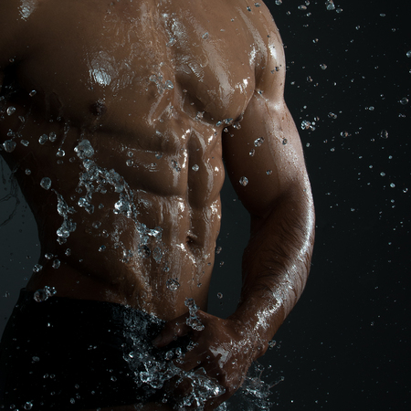 Sensual fashion portrait of a fit nude male model posing against bright whiteの写真素材