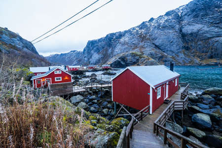 Traditional red fishing houses, called rorbu, in town of Nusfjord on Lofoten islands in Norway during a cloudy winter day.の写真素材