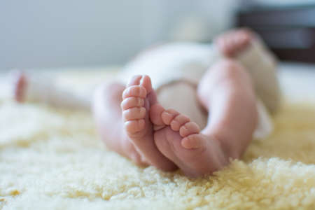 Close-up of unrecognizable cute baby shaking feet while lying in bed.の写真素材