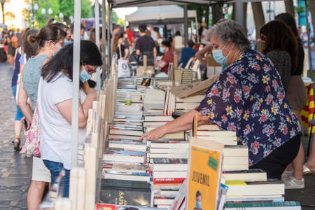 Tarragona, Spain - July 23, 2020: People looking at books with mask and hydroalcoholic gel during Sant Jordi feast in Tarragona, Catalonia.のeditorial素材