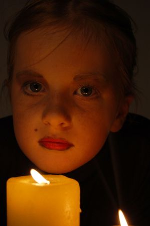 young girl in candlelight with big eyesの写真素材