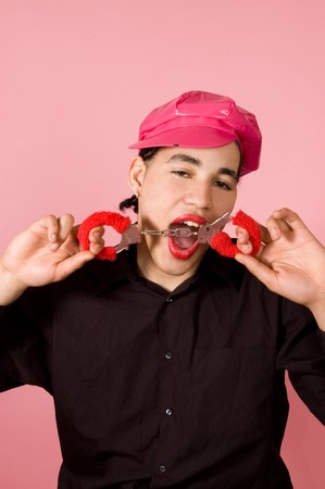 drag-queen is biting on a pair of handcuffs on pinkの写真素材