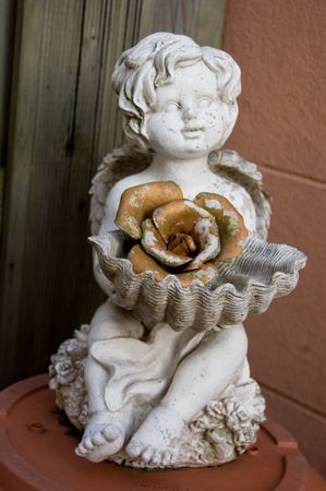small angel sculpture with golden flowerの写真素材
