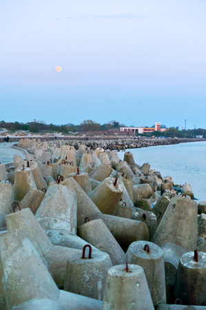 concrete breakwaters protecting the sea shore, pier sea and coastal fortifications, full moon and sea pierの写真素材