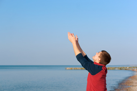 the young man raises his hands up, the young man raises his hands to the sun on the beachの写真素材