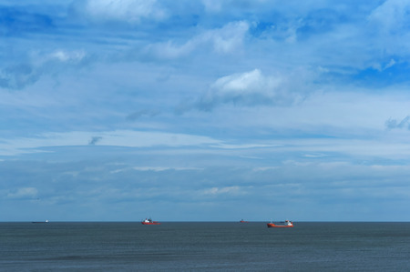 Oil drilling in the sea, ships in the sea on the horizon, calm and cloudy skyの写真素材