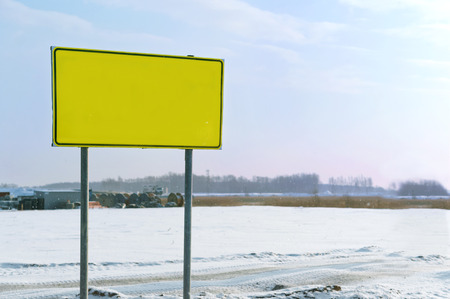 yellow warning sign, signpost stand on the road in winterの写真素材