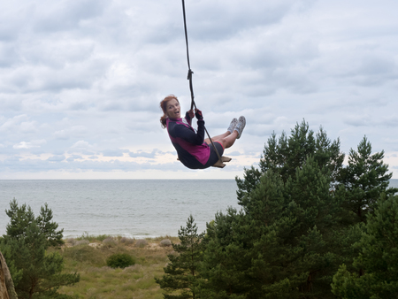 girl swinging on a swing, rope swing over the seaの写真素材