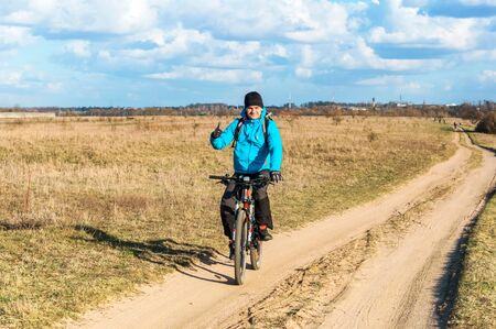 lonely bike traveler, young man in a blue jacket on a Bicycle, Kaliningrad, Russia, Eastern Europe, March 31, 2019のeditorial素材
