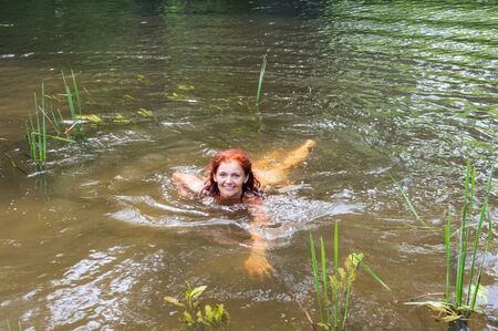 girl swims in the river, brunette swims in the pond, the river Angrapa, Kaliningrad region, Russia, June 15, 2019のeditorial素材