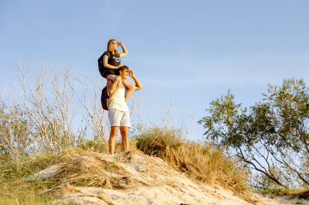 the girl sits on the neck of a man, a girl on a man's shoulders, a young couple peering into the distance, Curonian spit, Zelenograd district, Kaliningrad region, Russia, August 31, 2019のeditorial素材
