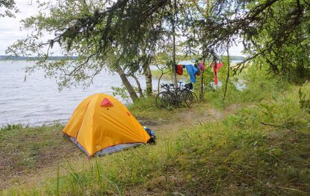 tourist tent on the shore of the pond, yellow tent on the shore of the lake, vishtynets lake, Kaliningrad region, Russia, July 31, 2019のeditorial素材
