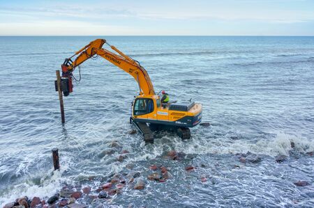 manipulator works with piles, construction of breakwaters in the sea, Baltic sea, Svetlogorsk, Kaliningrad region, Russia, November 17, 2019のeditorial素材