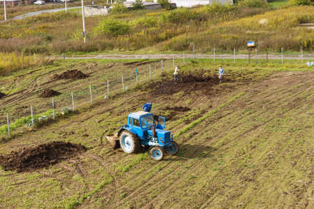 fertilizing fields, blue tractor fertilizing a field, farmers spreading fertilizer with shovels, Kaliningrad region, Russia, September 29, 2019のeditorial素材