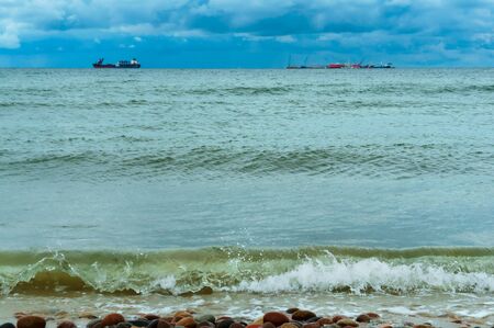 Baltic sea coast, small waves on the sea, ships on the sea horizonの写真素材