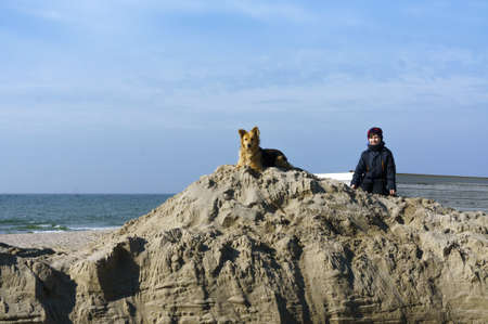 a boy with a dog on the sand, a child with his dog playing on the coast, Baltic sea, Russia, Kaliningrad region, March 09, 2020のeditorial素材