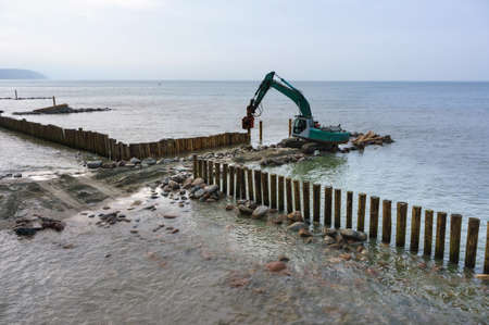 construction equipment on the shore, the construction of breakwaters, coastal protection measures, Baltic sea, Russia, Kaliningrad region, February 15, 2020のeditorial素材