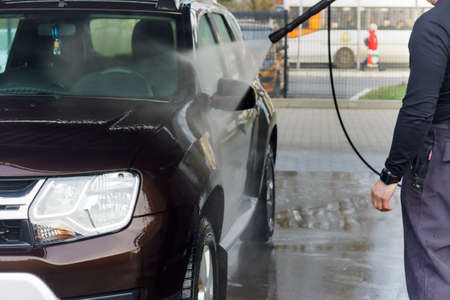 a man washes a car at a contactless car wash, a man washes a brown car, Kaliningrad, Russia, March 1, 2020のeditorial素材