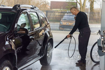 a man washes a car at a contactless car wash, a man washes a brown car, Kaliningrad, Russia, March 1, 2020のeditorial素材