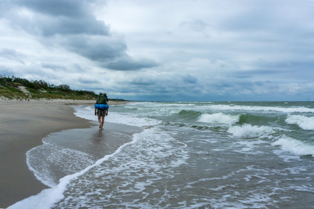 Baltic sea, Russia, Kaliningrad region, July 5, 2020, a man with a large backpack, a tourist walks along the sea coastのeditorial素材