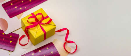 Yellow gift on a beige background. Beige background. Yellow Gift box with red ribbon.の写真素材