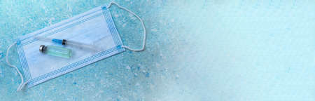 Medical instruments on blue background. Banner with medical items. Medical mask and vaccine. Ampoule of medicine and syringe.の写真素材