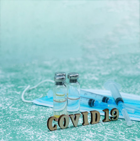 Prevention of seasonal diseases. Medical ampoules, syringes, and a mask on a green background.の写真素材