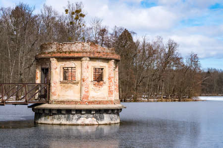 Kaliningrad region, Kolosovka (Willgaiten, Vikau), Russia, March 20, 2021. The gate tower on the pond. Drainage system of the lake. A linden alley on the shore of the lake.のeditorial素材