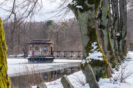 Kaliningrad region, Kolosovka (Willgaiten, Vikau), Russia, March 20, 2021. The gate tower on the pond. Drainage system of the lake. A linden alley on the shore of the lake.のeditorial素材