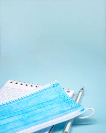 Stationery items and sanitary mask. Medical mask and notepad on blue background.の写真素材