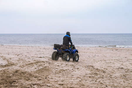 Kaliningrad Region, Russia, 11 April 2021. The quad bikes on the sea beach. Riding on a quadricycle. A man rides a quadricycle on the sand.のeditorial素材